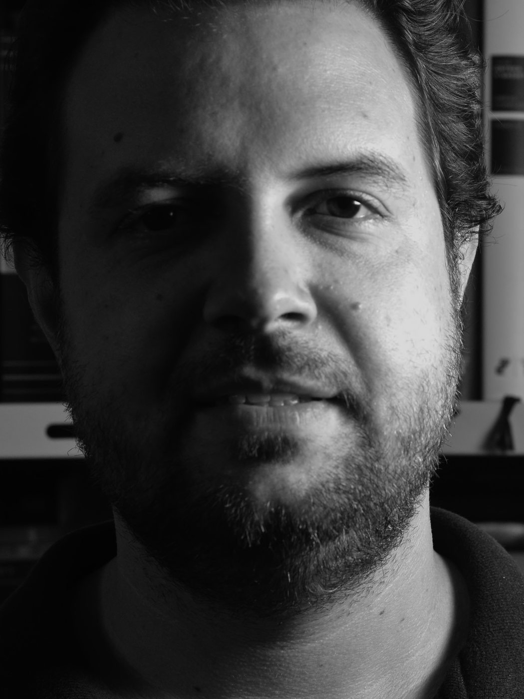 Martim Vasques da Cunha diante de uma estante de livros